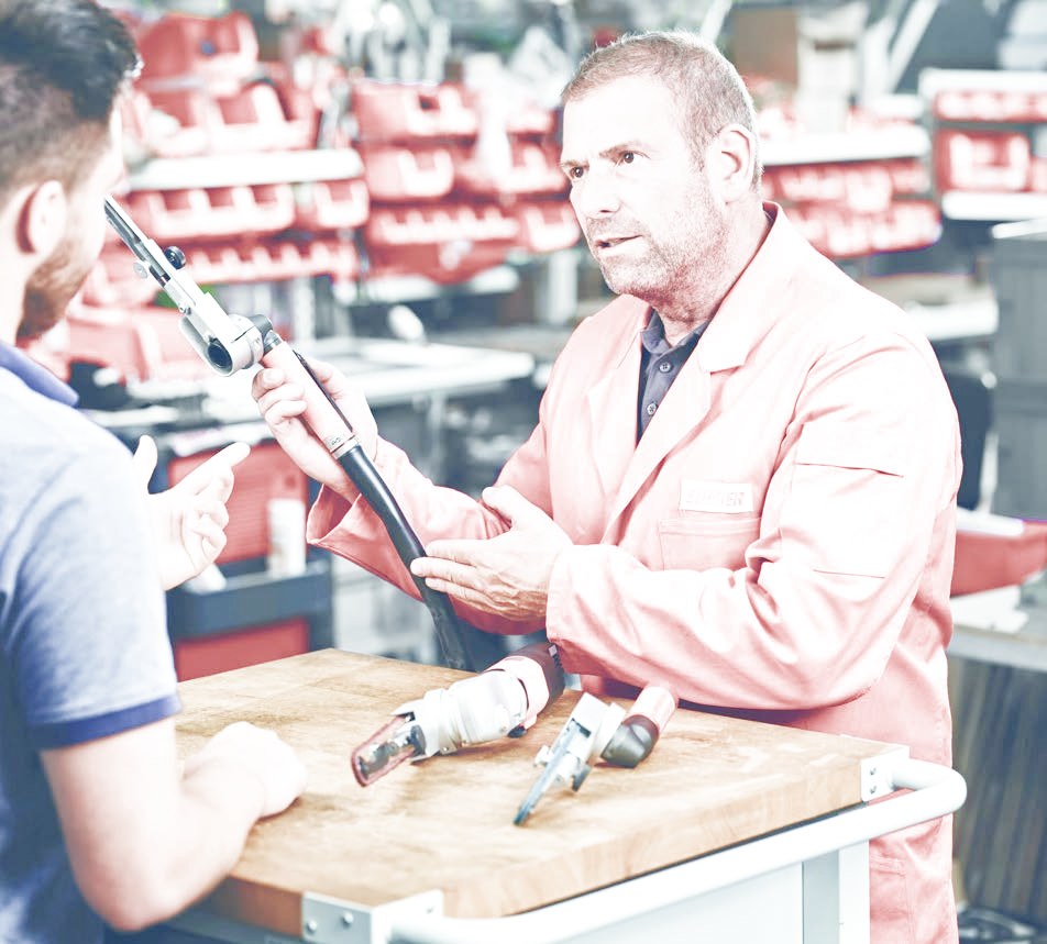 Specialist explaining abrasive belt tools to a customer at the workbench